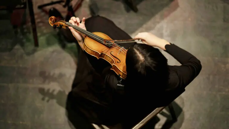 View of a woman from above, dressed in black, as she holds a violin.