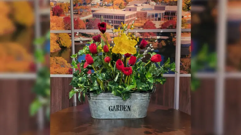 A floral arrangement sits on a table with the word "Garden" on the tin pot.