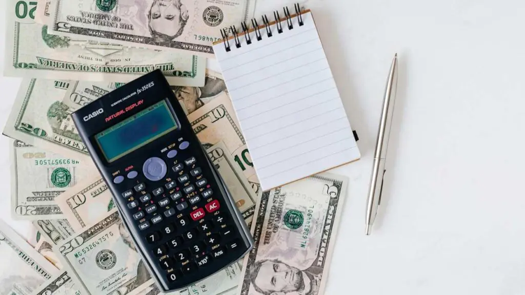 money bills sitting underneath a calculator and notepad to signify finances