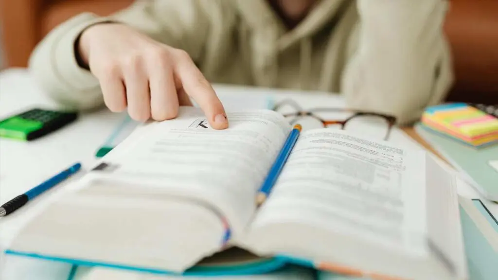 Student looking at book with finger on page