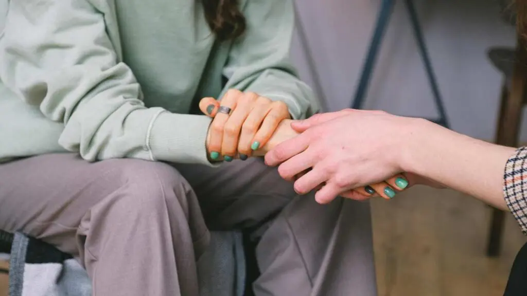 2 people holding hands, for story on mental health aid