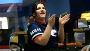 Grace Kaufman smiles and claps at a bowling match for Naperville North.