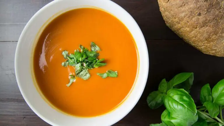 Soup bowl filled with tomato soup with bread and herbs in shot for story on Souper Bowl Stroll