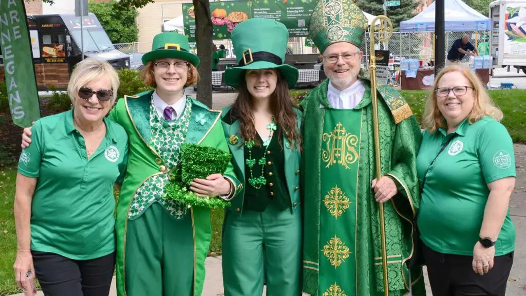 A group dressed in green and shamrocks posing with a man dressed as St. Patrick.