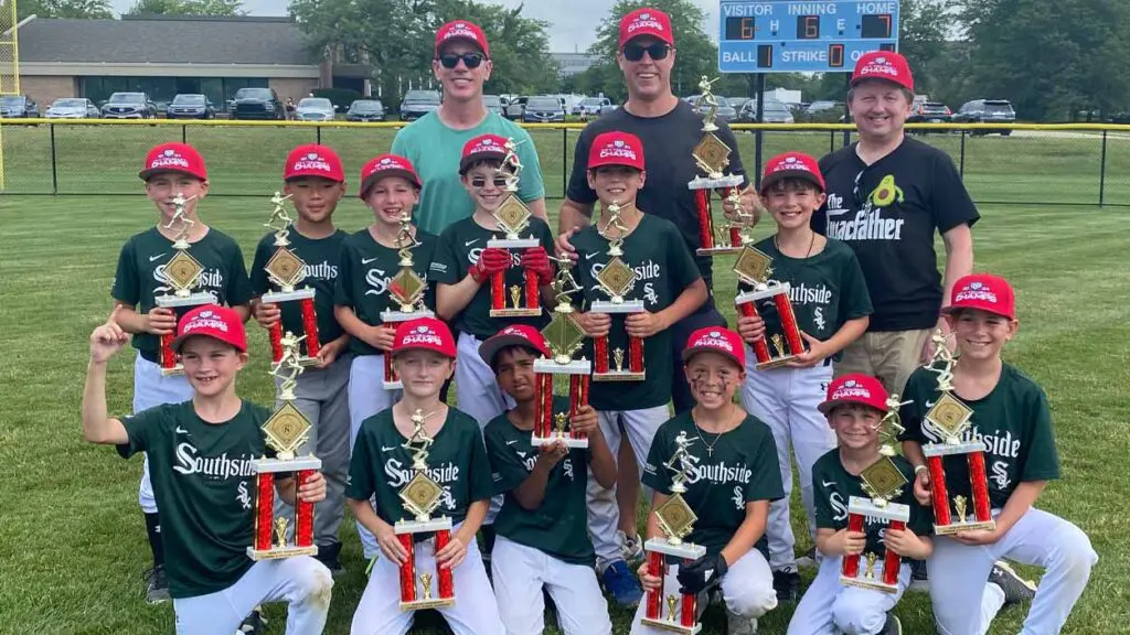 A little league team holds their trophies.