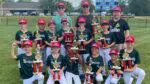 A little league team holds their trophies.