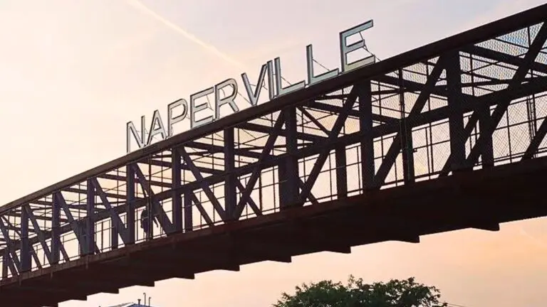 Naperville sign on pedestrian bridge with sunset in background