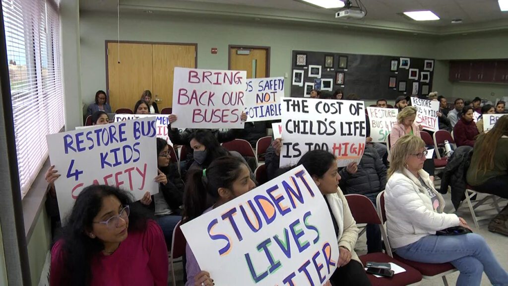 Parents holding signs regarding busing concerns