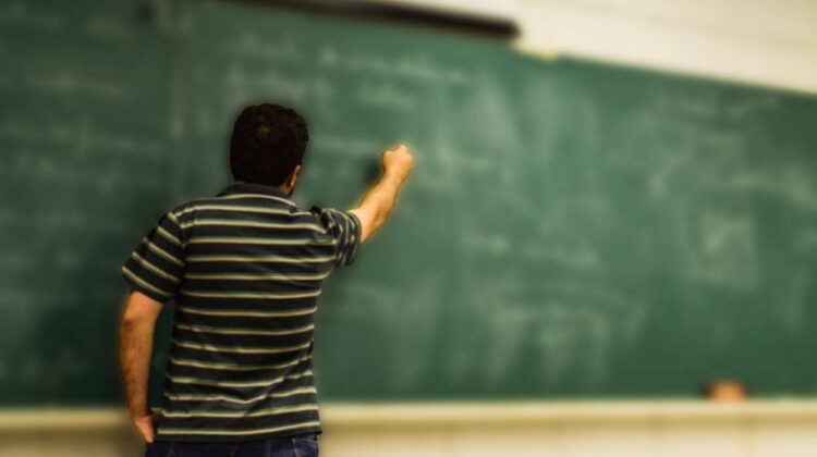 teacher writing on chalkboard stock image