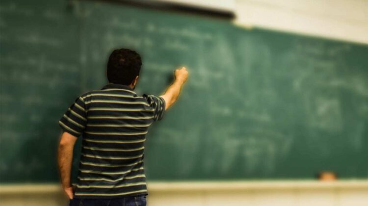 Teacher writing on chalkboard