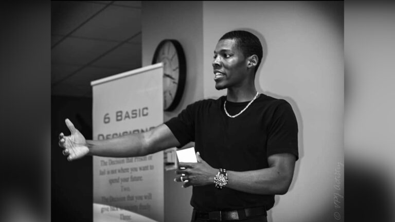 A man in a black t-shirt gives a presentation.