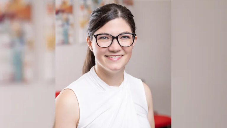 A woman wearing glasses and a white shirt with her hair in a pony tail.