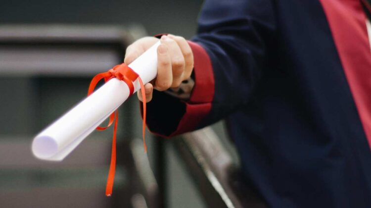 Person holding scroll with ribbon