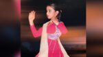 A young girl in a pink dress dances.