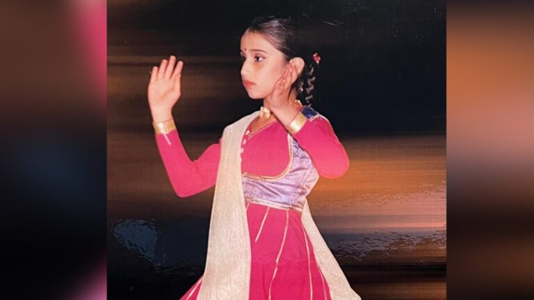 A young girl in a pink dress dances.