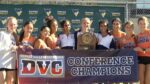 Naperville North girls cross country team smiles with the DVC championship trophy.