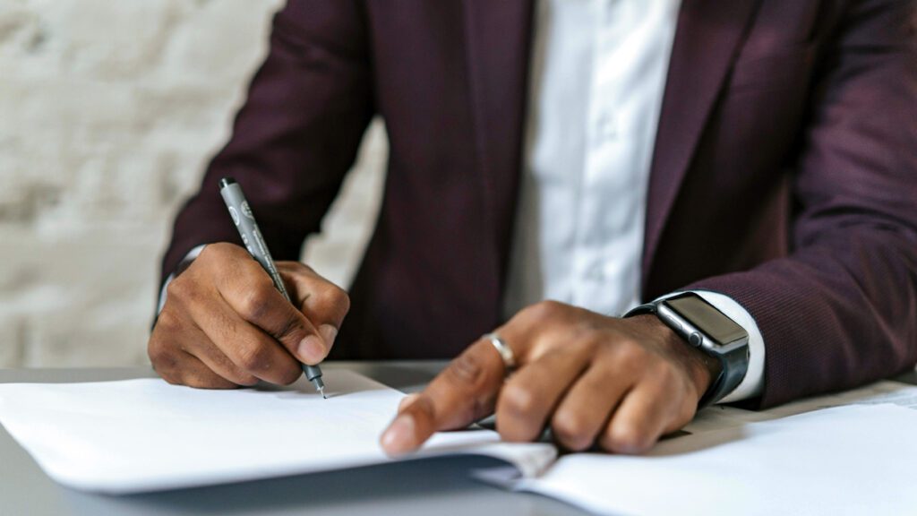 Close up of a man's hands that are signing a document.