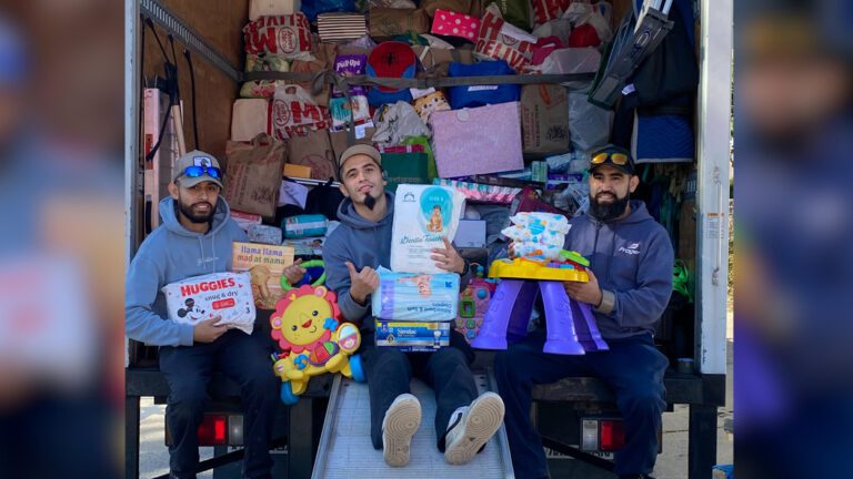 crew members with Prager Moving & Storage Company sit at the edge of a moving truck filled with donations for victims of Hurricane Helene