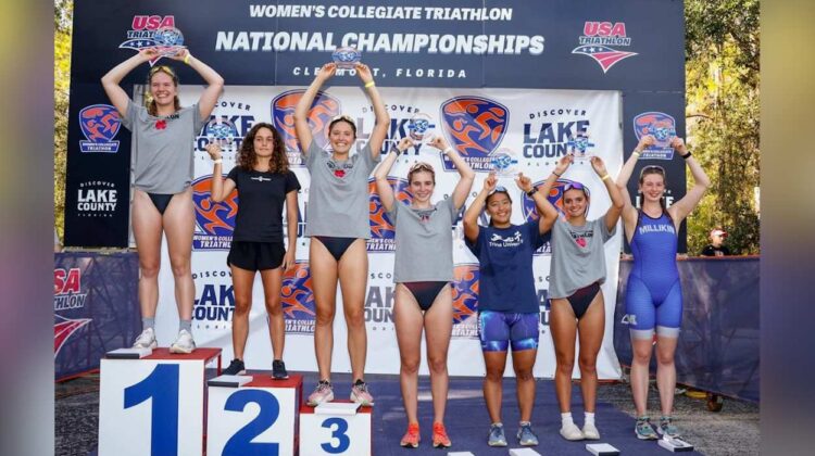 North Central Womens Triathlon members from the top seven smile at the podium.